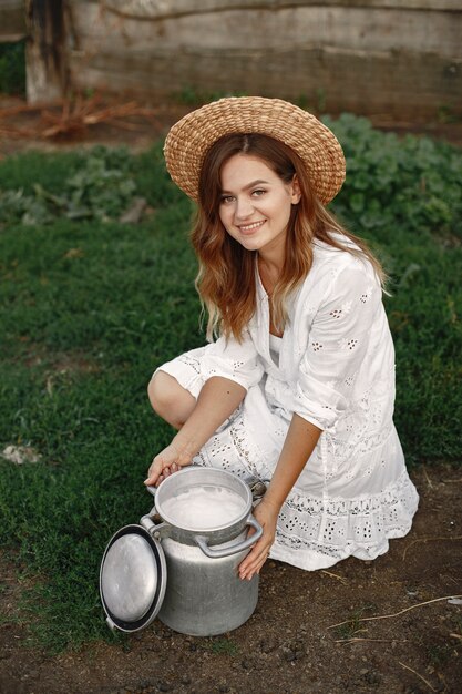 Woman in a summer field. Girl in a white dress. Woman with barrel of milk.