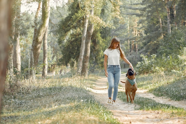 woman in a summer forest playing with dog