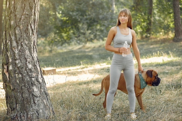 woman in a summer forest playing with dog