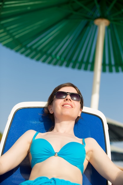 Woman sunbathing under green sun umbrella