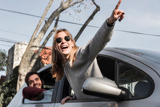 Woman in sunglasses hanging out of car window 