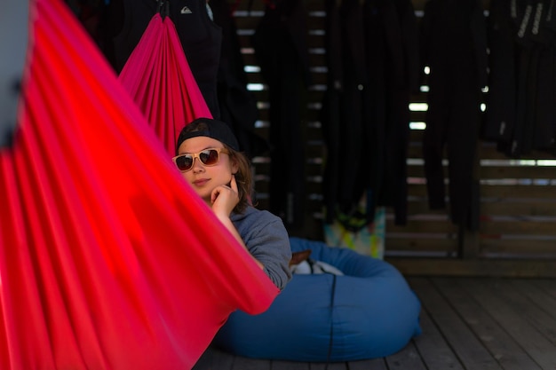 A woman in sunglasses lies in a red hammock