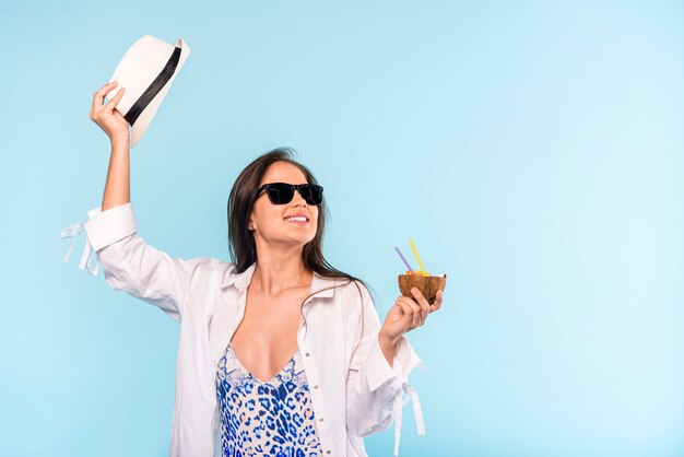 Woman in sunglasses with hat smiling and holding cracked coconut