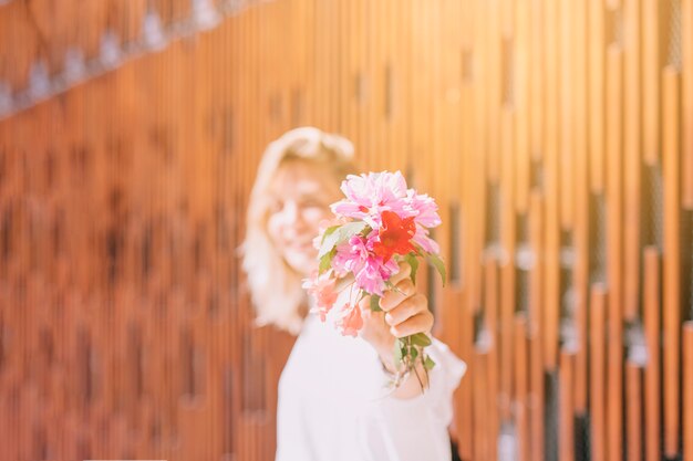 카메라를 향해 꽃을 보여주는 햇빛에 여자