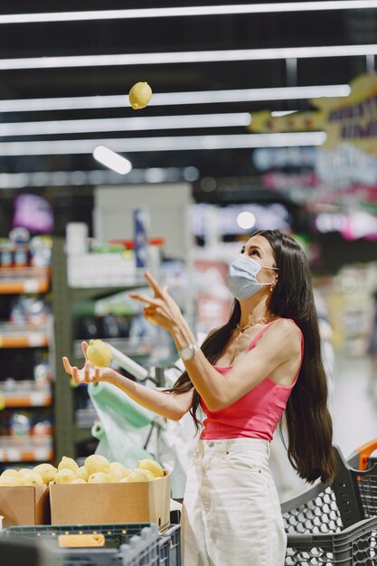 Woman in a supermarket. Lady in a respirator. Girl makes parchases.