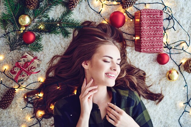 Женщина окружает рождественские огни, лежа на полу и мечтает