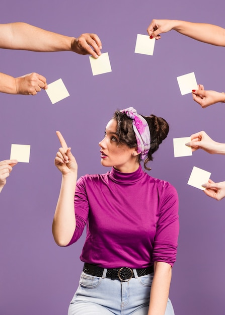 Woman surrounded by hands and sticky notes picking an empty note