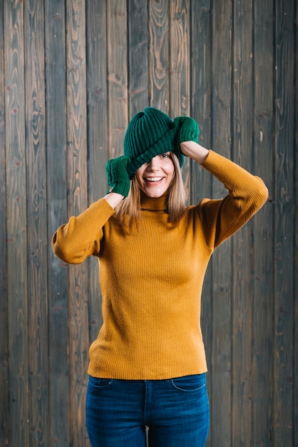 Free photo woman in sweater covering face with cap