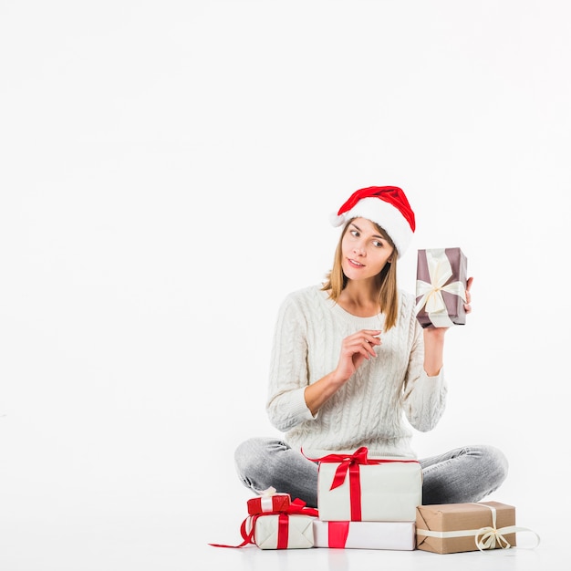 Woman in sweater holding gift box near ear