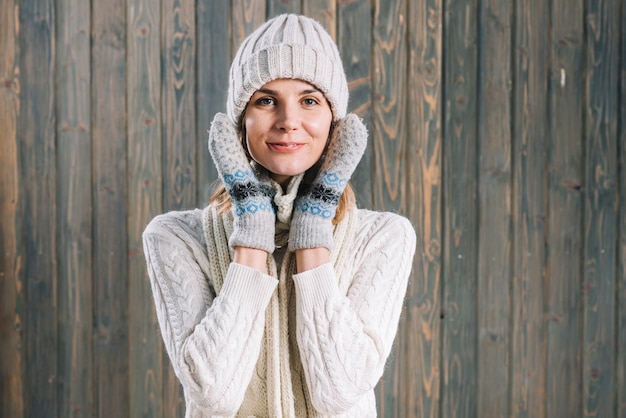 Woman in sweater holding hands on cheeks 