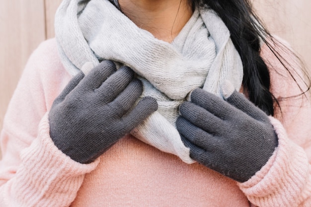 Donna in maglione che tiene le mani sulla sciarpa