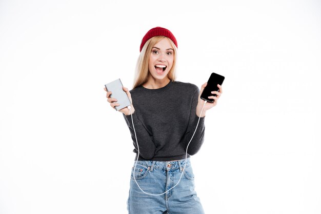 Woman in sweater holding power bank and smartphone