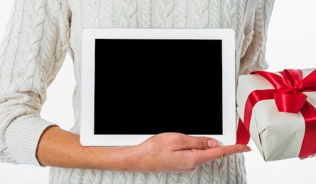 Woman in sweater holding tablet and gift box 