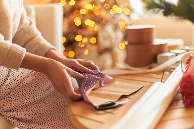 Woman in sweater sitting and wrapping gifts
