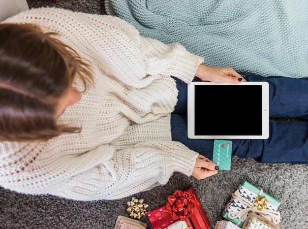 Woman in sweater using card for payment on tablet 