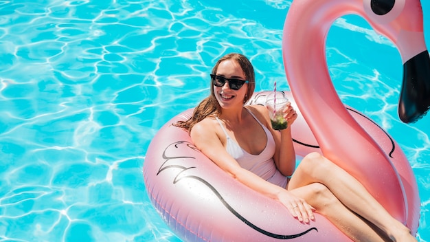 Foto gratuita donna in anello di nuotata godendo il suo cocktail