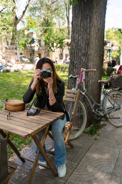 Woman in synthetic leather jacket using camera while outdoors