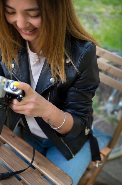 Woman in synthetic leather jacket using camera while outdoors