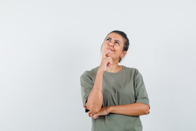 woman in t-shirt holding finger on chin and looking hesitant