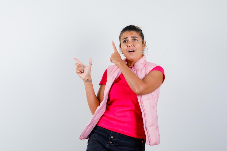 मुफ़्त फोटो woman in t-shirt, vest pointing finger up and looking confused 