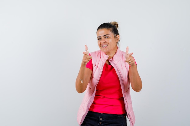 Woman in t-shirt, vest showing gun gesture and looking confident 