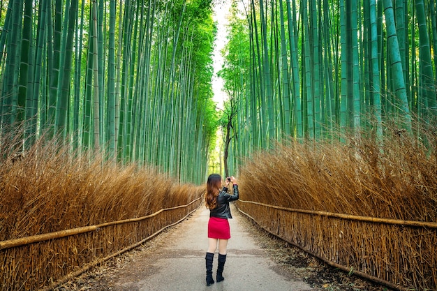 京都の竹林で女性が写真を撮る。