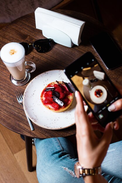 Woman takes photo of her strawberry dessert with her smartphone