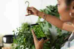 Free photo woman takes a photo of houseplant to share on social media