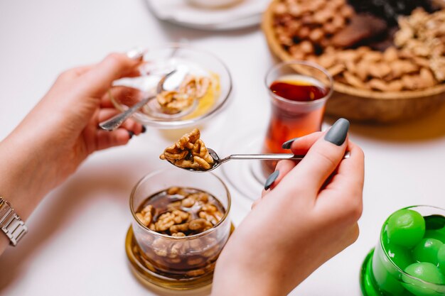 Woman takes walnut jam in saucer tea side view