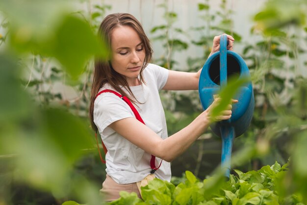 Женщина ухаживает за растениями в теплице