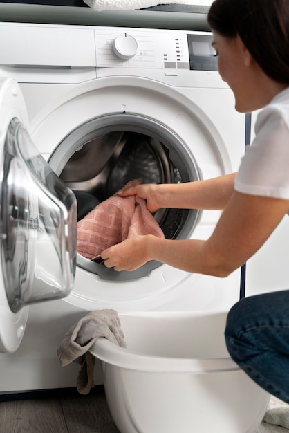 Free photo woman taking clothes from the washing machine