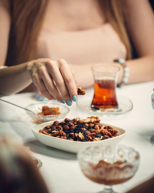 Woman taking nuts from white plate.