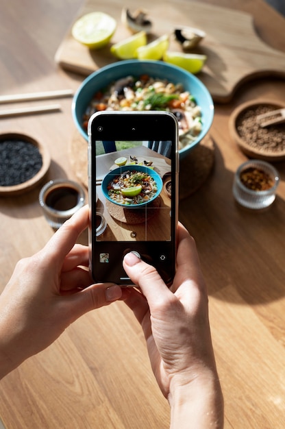 ラーメンとスライスしたレモンのボウルの写真を撮る女性