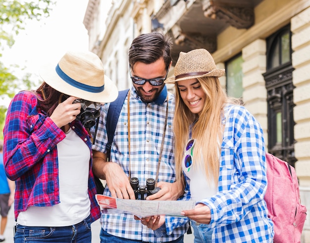 Woman taking photo on camera while her friends looking at map