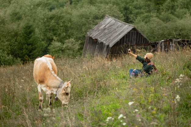 Free photo woman taking a photo next to a cow