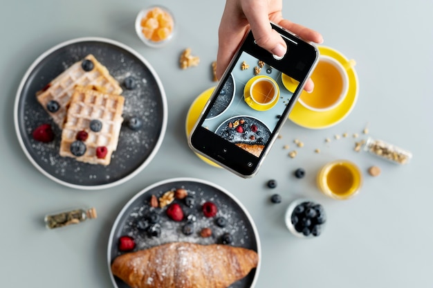 Woman taking photo of cup of tea and berries