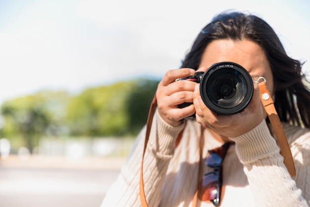 ぼかしの背景を持つ日中に写真を撮る女性