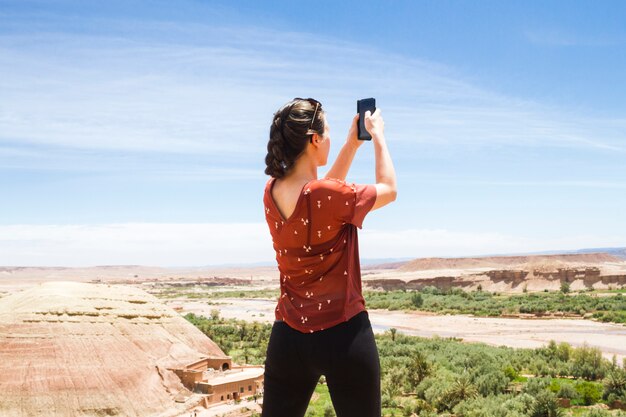 Женщина принимая фото в пустынном ландшафте сзади