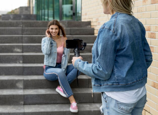 スマートフォンで友達の写真を撮る女性