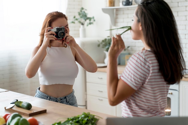 キッチンで彼女のガールフレンドの写真を撮る女性