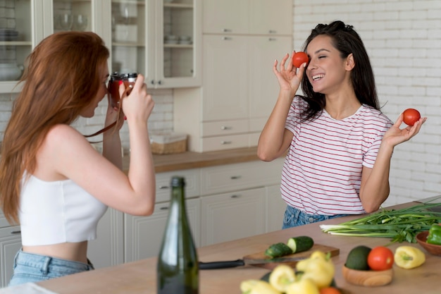 Woman taking a photo of her girlfriend in the kitchen