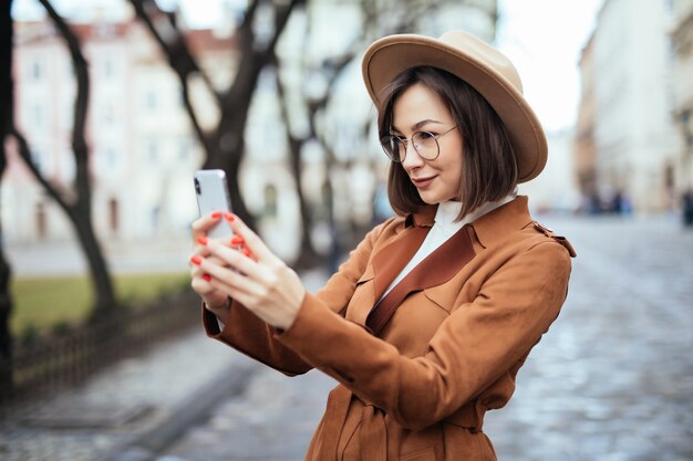 Woman taking photo on her phone in autumn day outside