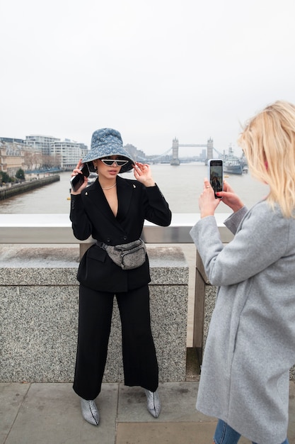 Free photo woman taking photo of internet celebrity on a bridge in the city