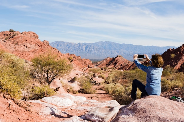 Woman taking photo of mountain landscape