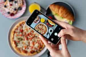 Free photo woman taking photo of a sliced pizza and a cup of coffee