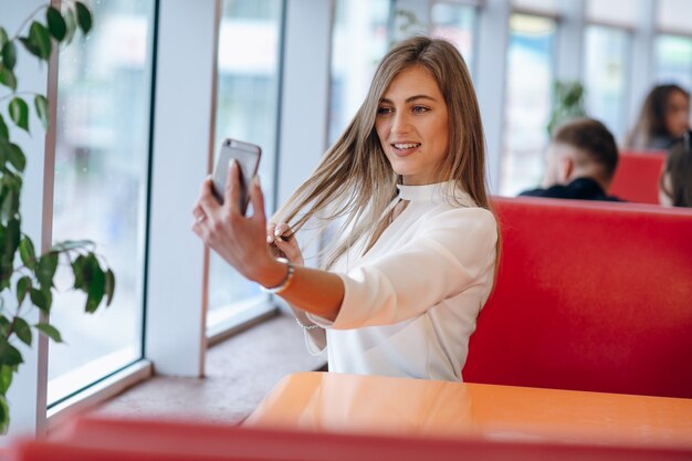 Woman taking a photo with her mobile to herself while touching her hair