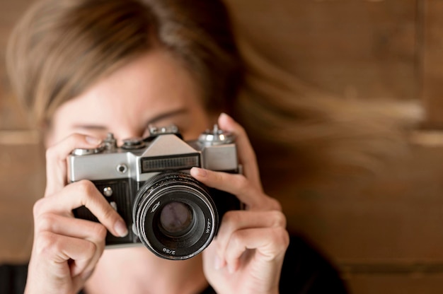 Woman taking a photo with retro camera close-up