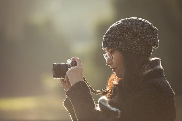 公園でデジタルカメラで写真を撮る女性