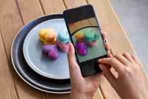 Free photo woman taking photos of heart-shaped macarons on planes with smartphone