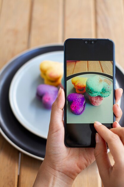 Woman taking photos of heart-shaped macarons on planes with smartphone